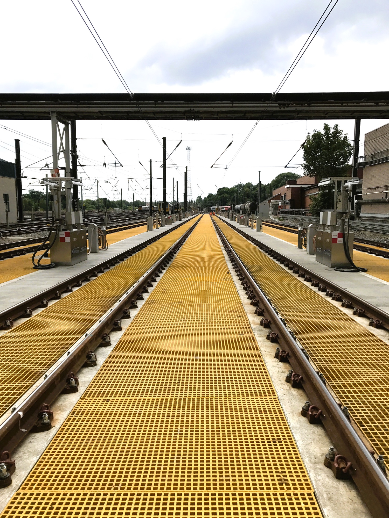 Installed yellow GRP grating trench covers providing access between railway tracks at Leeds Neville Hill depot